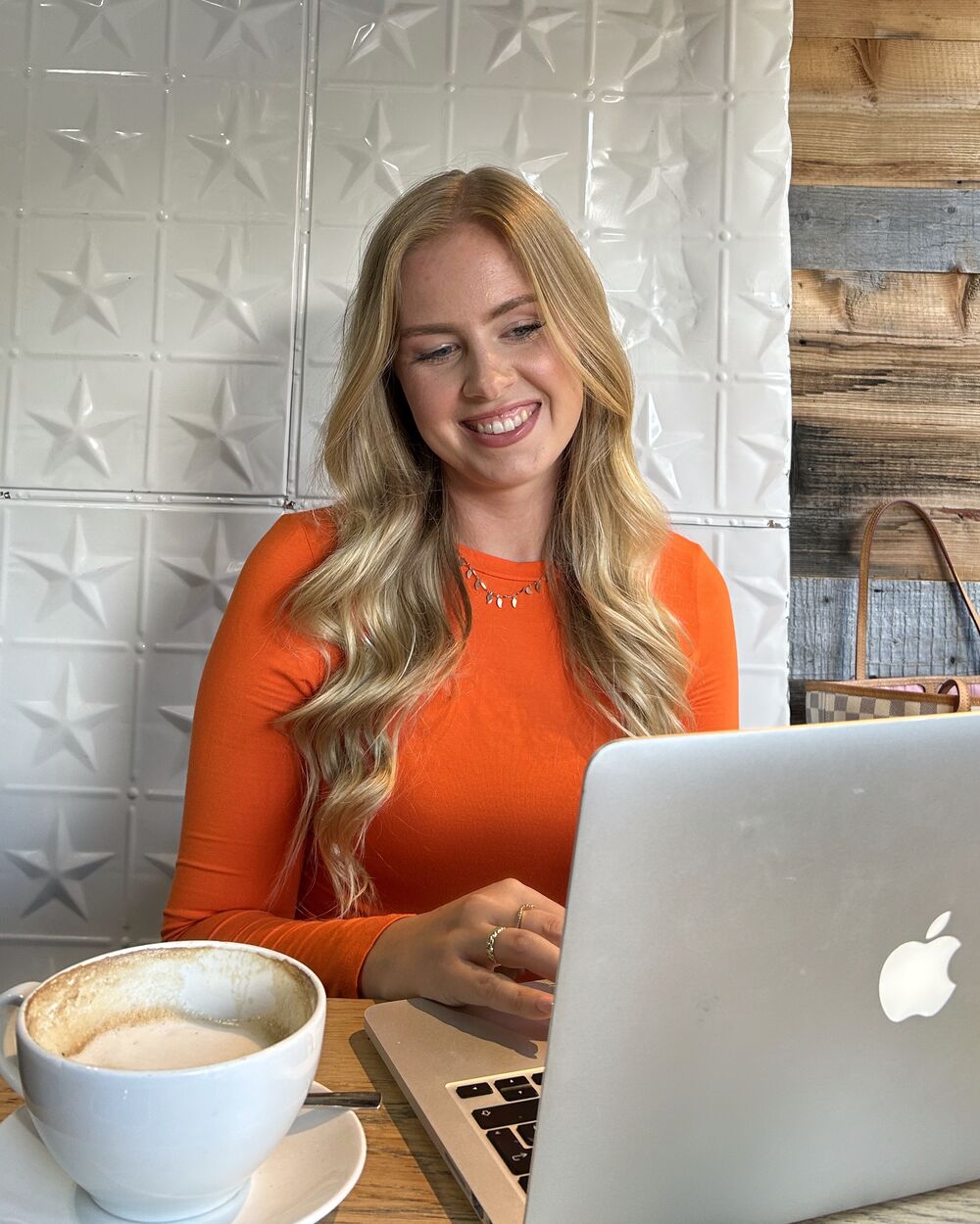 Nicola arbeitet mit Laptop und Kaffee in einem Café
